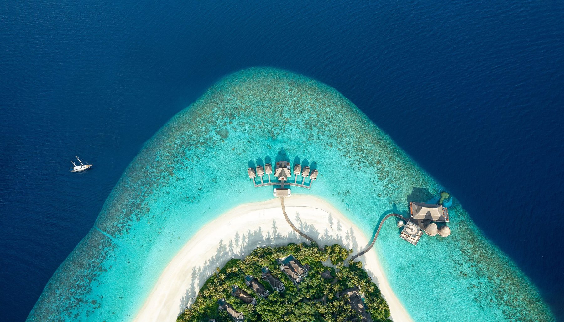 Ilha de coral rodeada por lagoa turquesa nas Maldivas, vista aérea