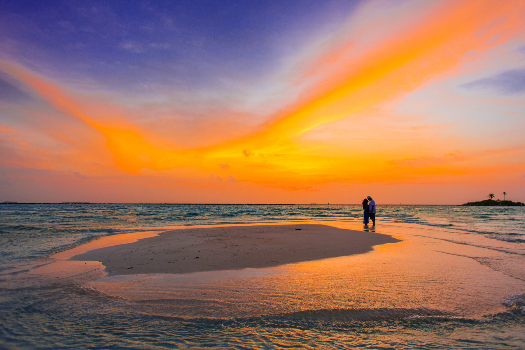 Casal ao pôr do sol num banco de areia nas Maldivas